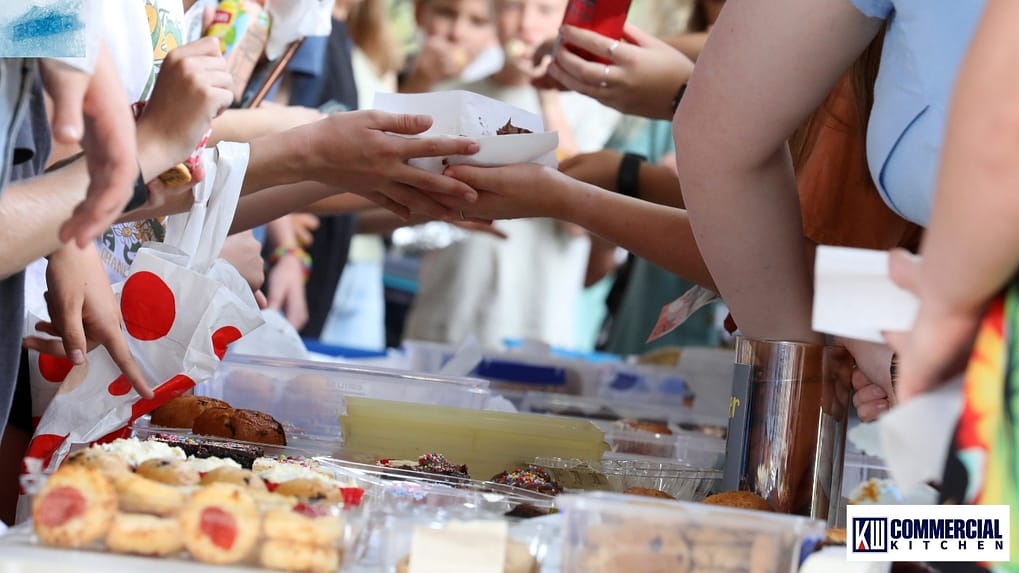 Community hall kitchen with upright glass-door fridge keeping fundraiser food cold at ≤5 °C