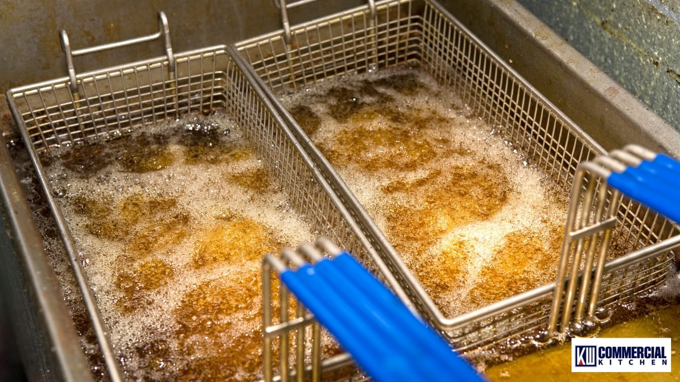 Basket of frozen chips being lowered into a commercial deep fryer