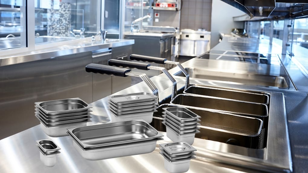 Chef portioning food into shallow 65 mm stainless steel GN pans for rapid cooling and FSANZ compliance in an Australian commercial kitchen